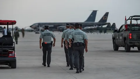 공항 활주로를 걷는 제복 차림 요원들